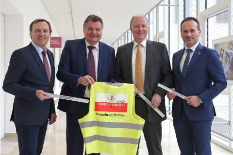 Politiker mit Warnwesten fordern Radfahrende auf sich sichtbar zu machen